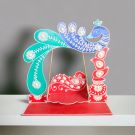 laddu gopal jhula with peacock design placed on table