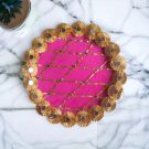pink gota and mirror work stainless steel decorative pooja thali placed on marble countertop - top view