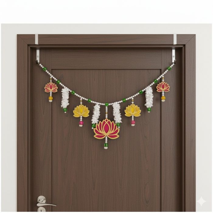 lotus, pearl and mogra toran hanging on dark colored wooden door 