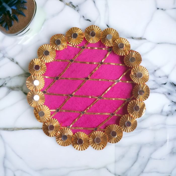 pink gota and mirror work stainless steel decorative pooja thali placed on marble countertop - top view