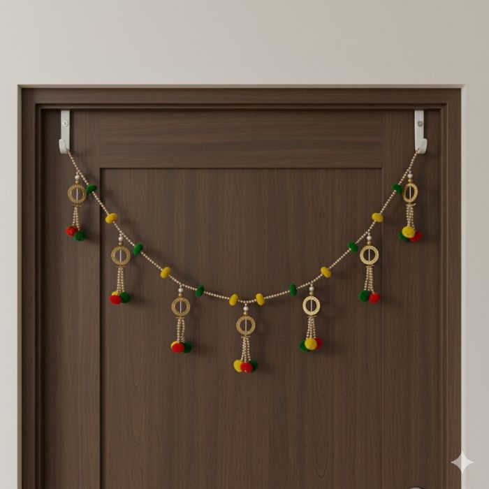 red, yellow, green pompom toran hanging on brown wooden door 