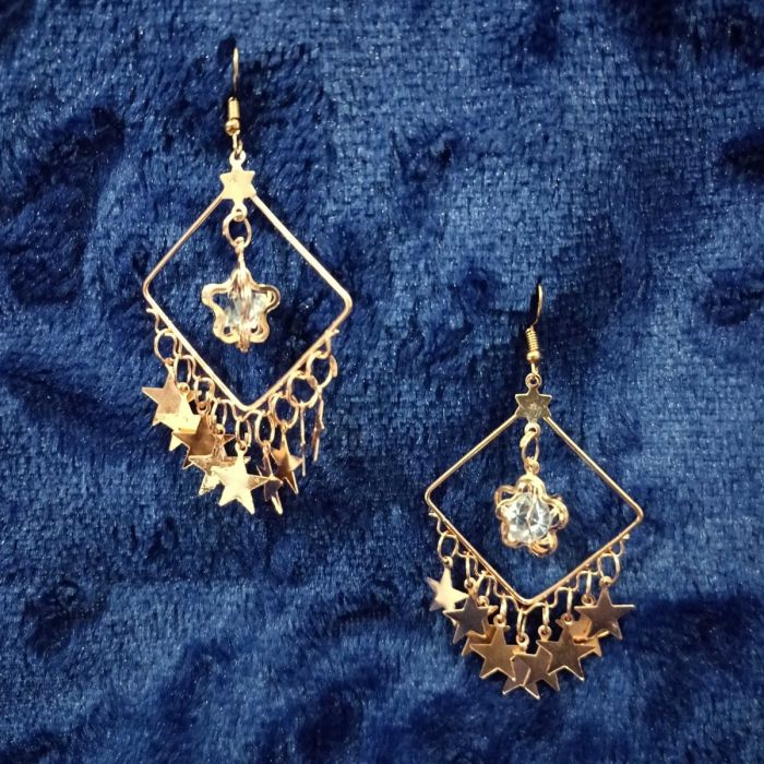 square shaped rose gold earrings - star fringes placed on dark blue velvet fabric