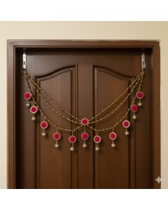 golden beads and pink pompom toran hanging on door