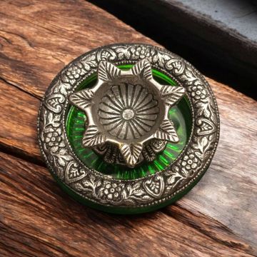 oxidized white metal diya on glass base placed on table top