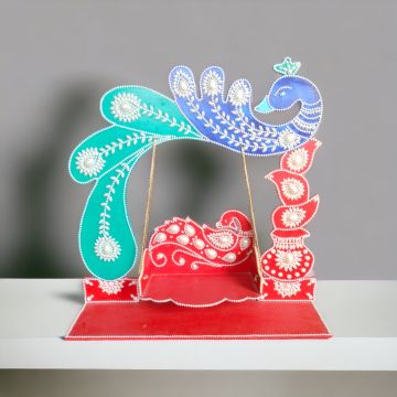 laddu gopal jhula with peacock design placed on table